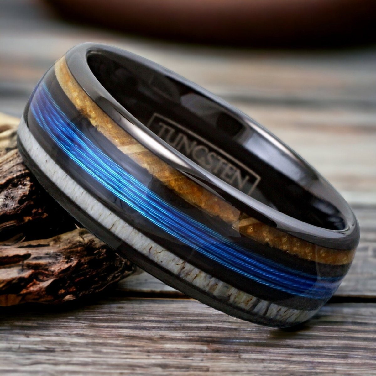 Unique men's wedding band featuring a black tungsten ring with deer antler, whiskey barrel wood, and fishing line inlay.